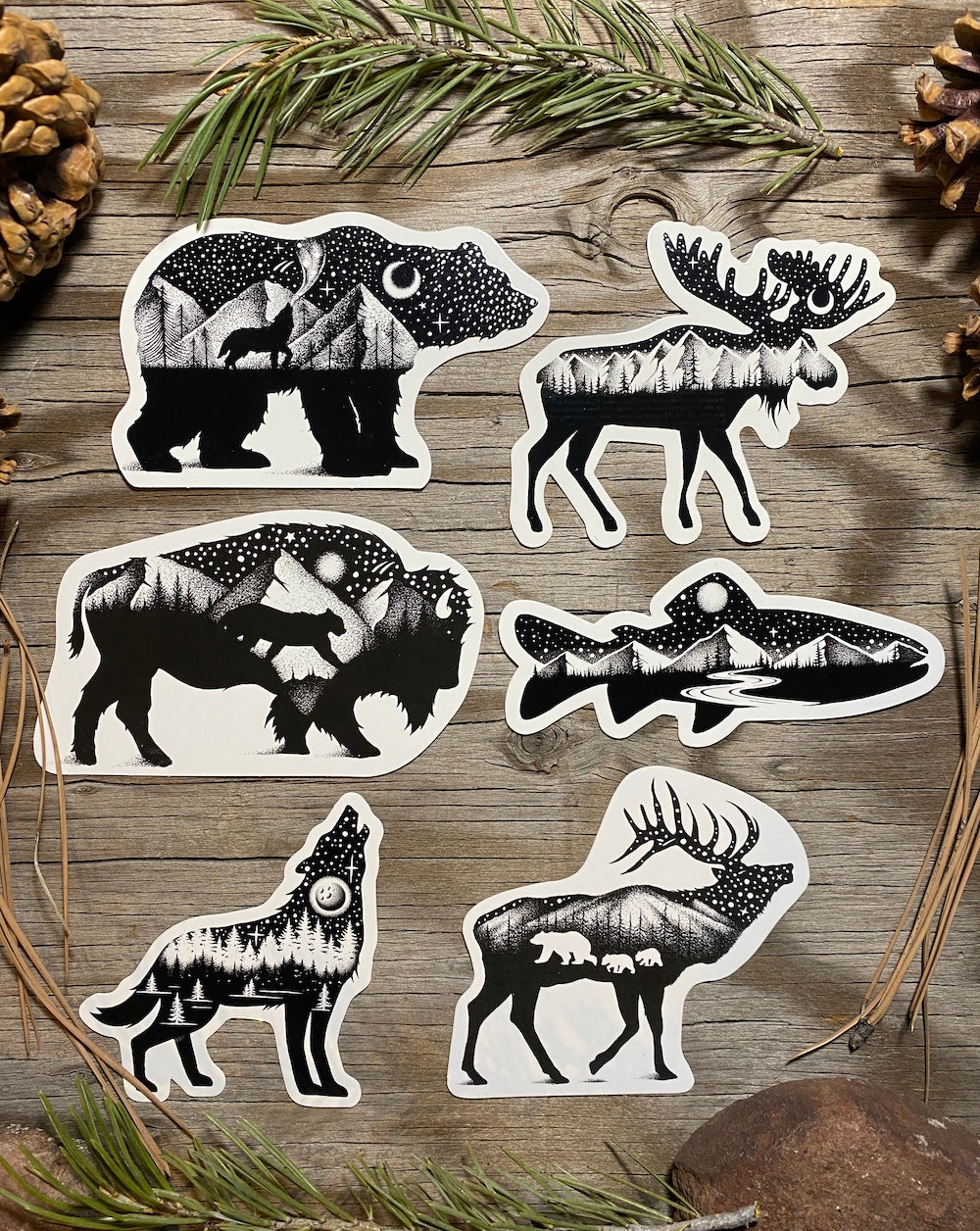 Six black-and-white bear, moose, bison, trout, wolf and elk wildlife stickers displayed on rustic wood