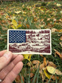 American Nature Flag sticker held in hand over fall leaves
