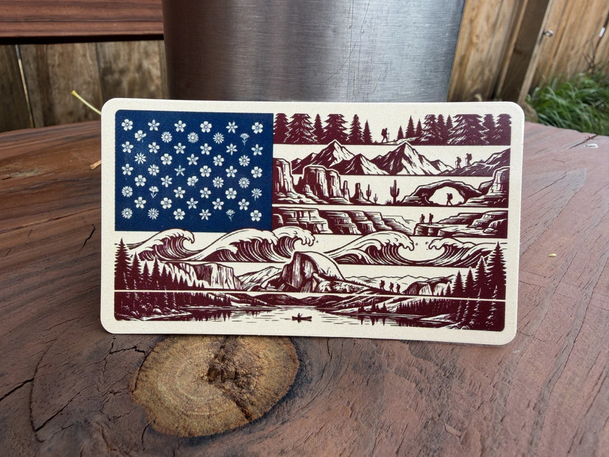 American flag sticker with wildflower stars and mountain, ocean and forest stripes on a wood stump