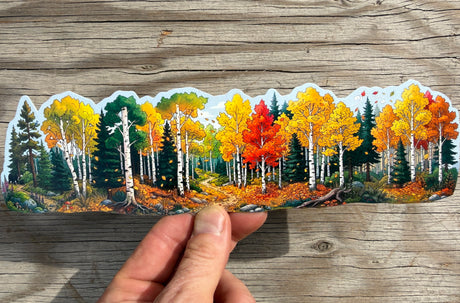 Autumn aspen forest water bottle wrap sticker held against rustic wood