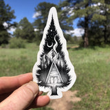 A-frame cabin beneath a crescent moon inside a pine tree sticker