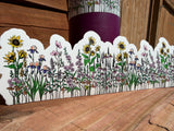 Wrap-around water bottle sticker with sunflowers and colorful wildflowers displayed on weathered wood