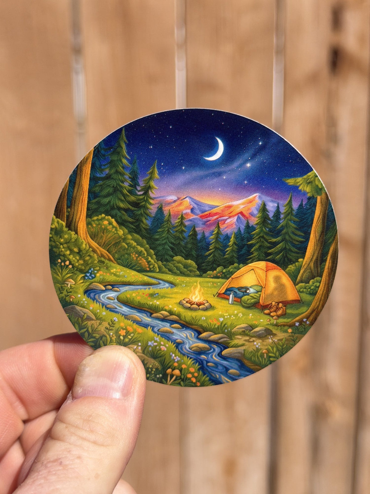 Night Camp round sticker held in hand with tent, campfire, creek and crescent moon
