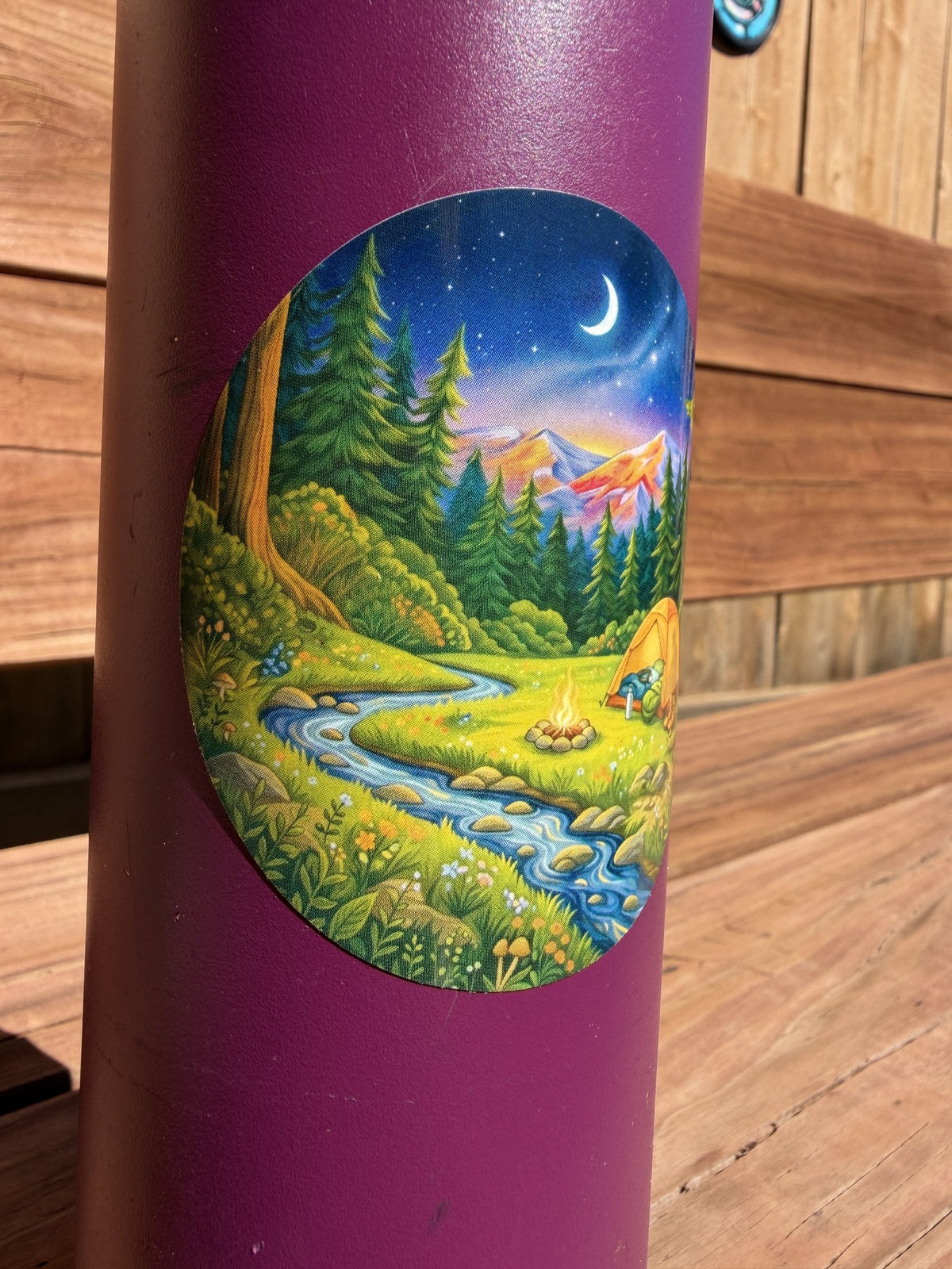 Close-up of round campfire and tent sticker on a water bottle