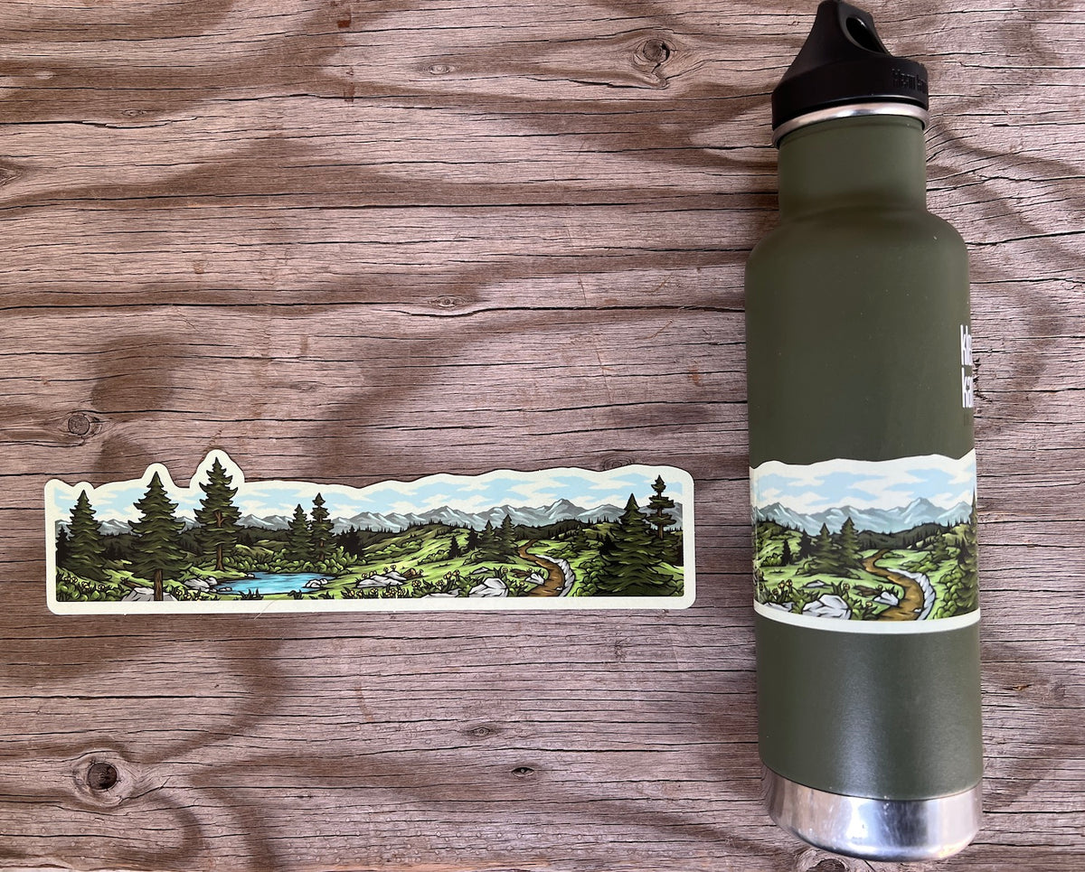 Mountain hiking and lake wrap sticker displayed beside an olive-green water bottle on a wooden background