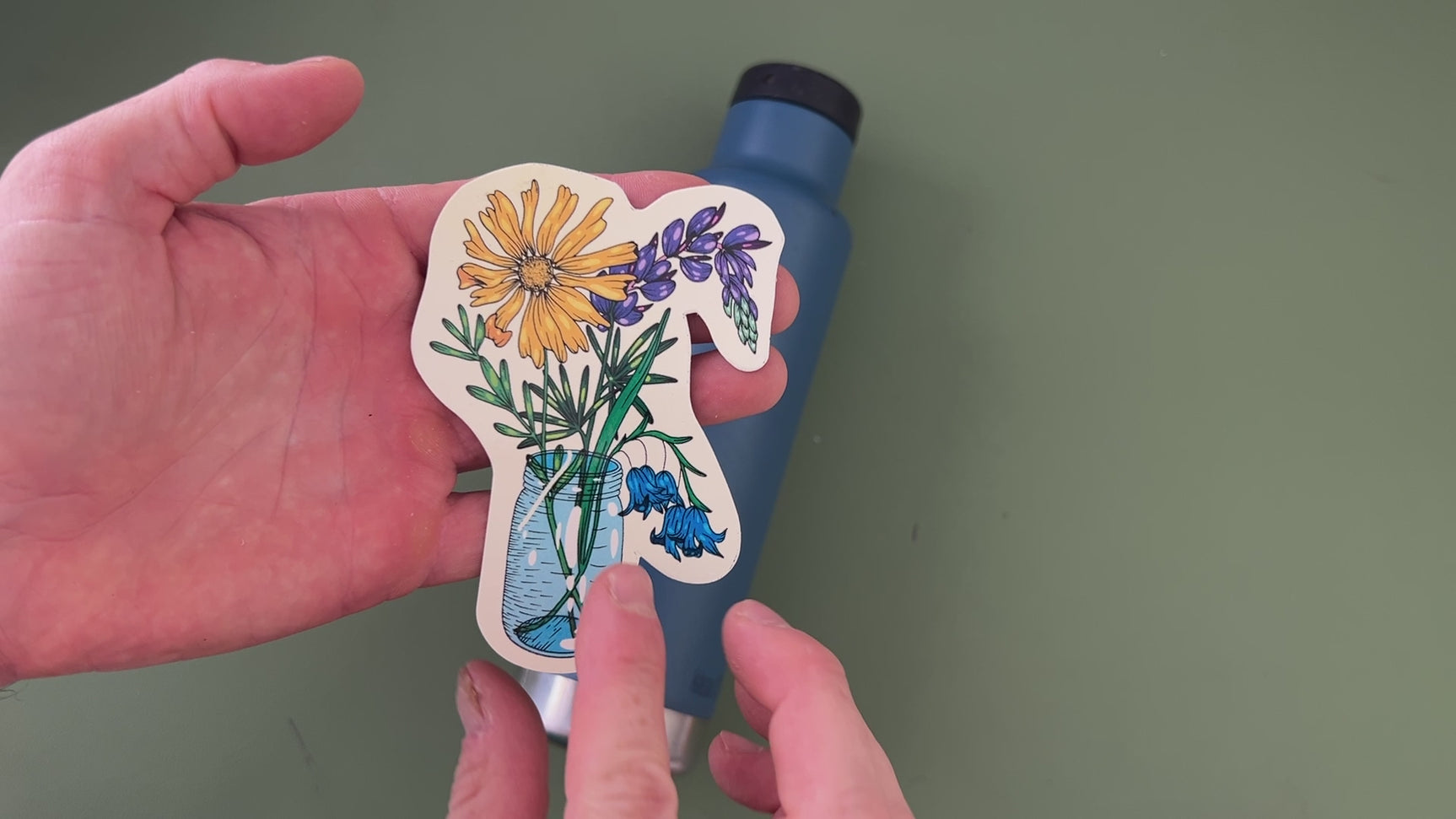 Applying a floral sticker from the wildflower pack to a water bottle