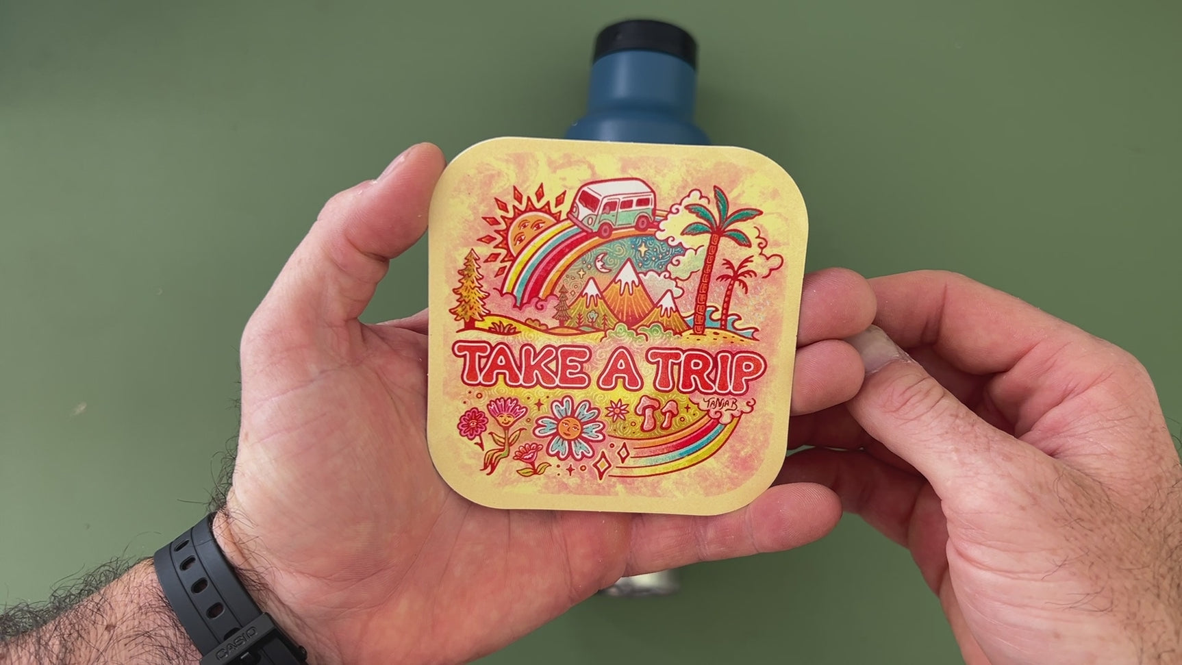 Applying the Take a Trip retro road trip sticker to a water bottle