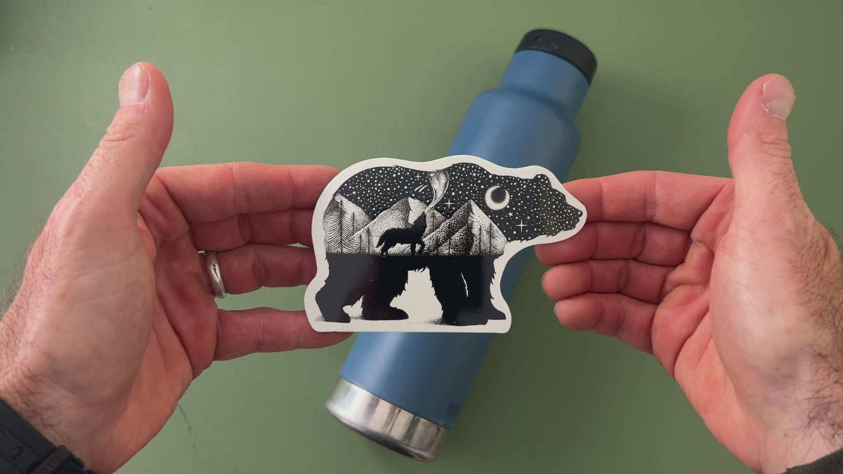 Applying the black bear and wolf wilderness sticker to a water bottle