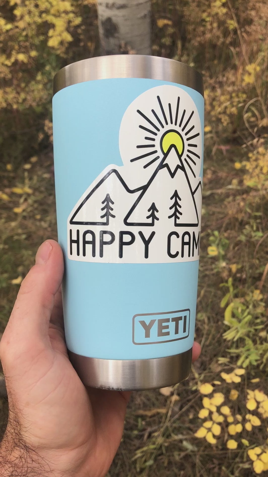 Applying the Happy Camper mountain sticker to a water bottle