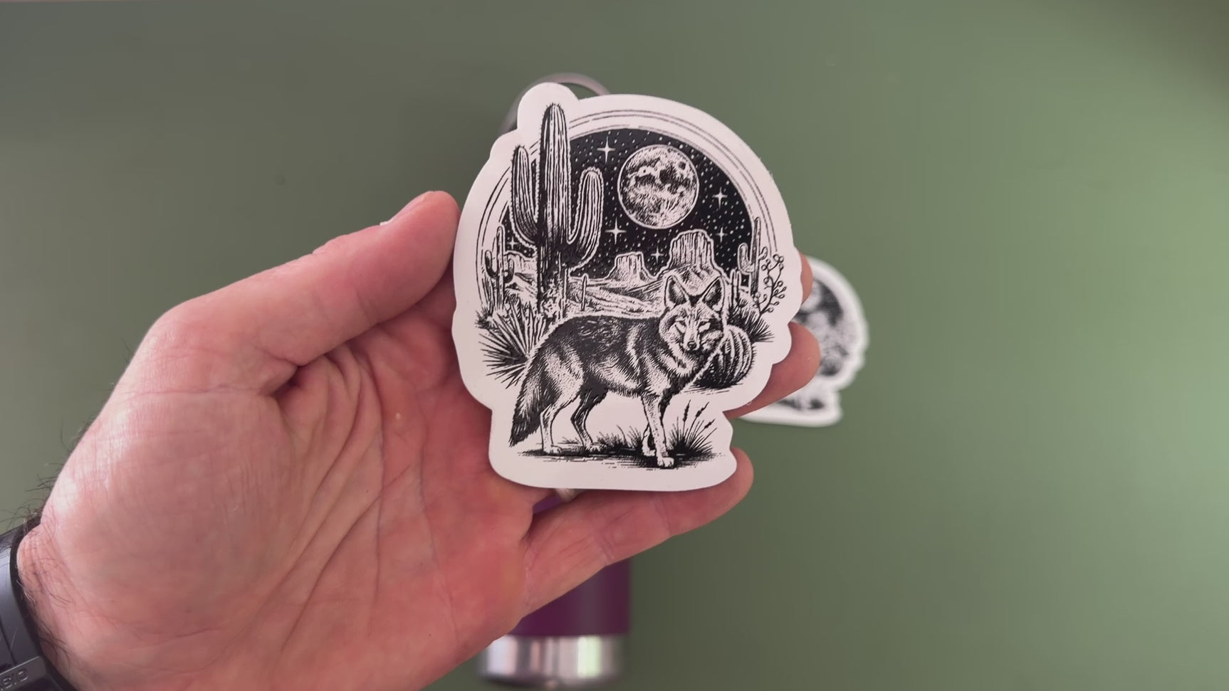 applying a die-cut coyote sticker to a water bottle