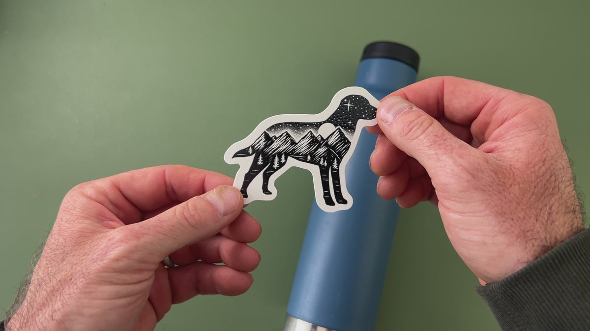 Applying the adventure dog sticker to a water bottle