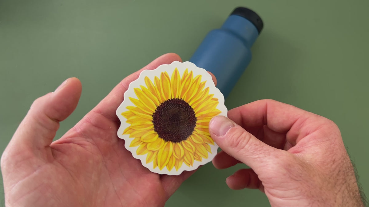Applying the yellow sunflower sticker to a water bottle