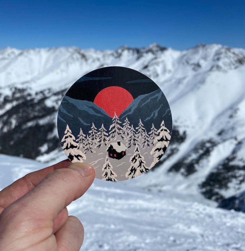 Snowy winter cottage, mountain sunset and pine forest vinyl sticker