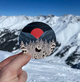 Snowy winter cottage, mountain sunset and pine forest vinyl sticker
