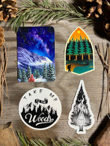 Four forest hiking, night sky and cabin stickers displayed on rustic wood